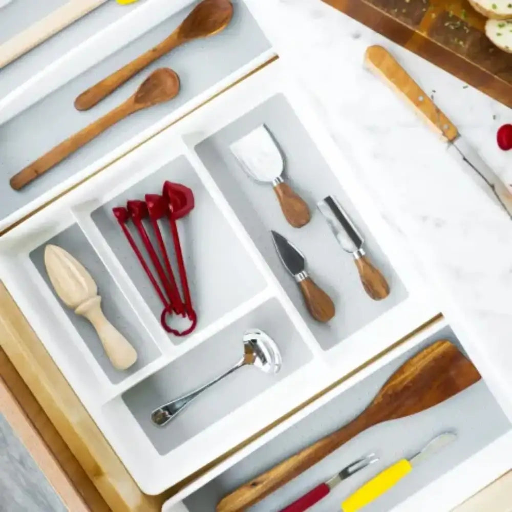 Kitchen utensils including wooden spoons, knives, and spatulas arranged in a drawer organizer.