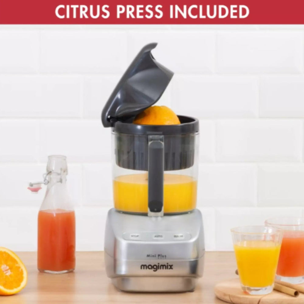 Magimix juice extractor with oranges, juice glasses, and a bottle on a wooden surface.