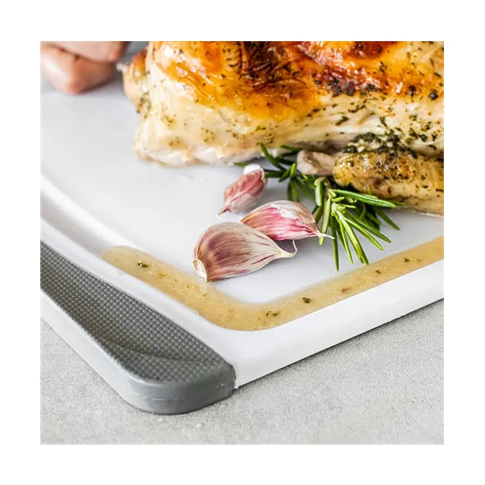 Roasted chicken on a cutting board with garlic and rosemary, on a light gray surface.