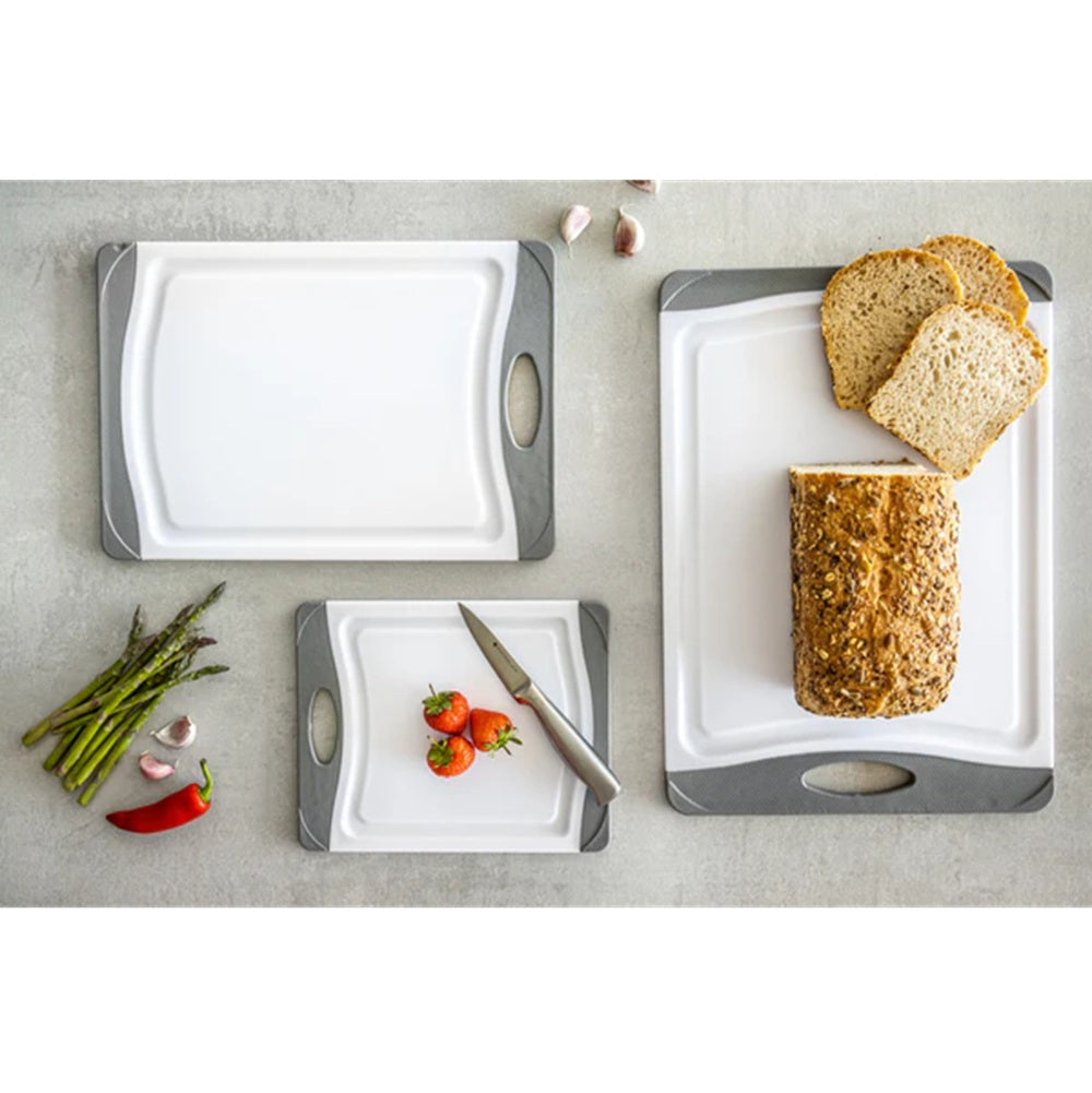 Set of cutting boards with bread, vegetables, and a knife on a light gray surface