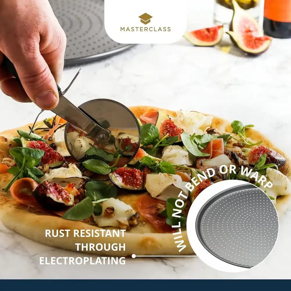 Person cutting a pizza with a pizza cutter on a marble surface, featuring a Masterclass branded pizza pan.