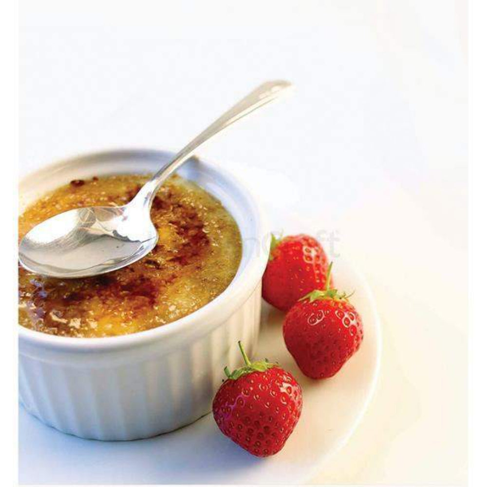 Creme bréleé with a spoon and strawberries on a white background