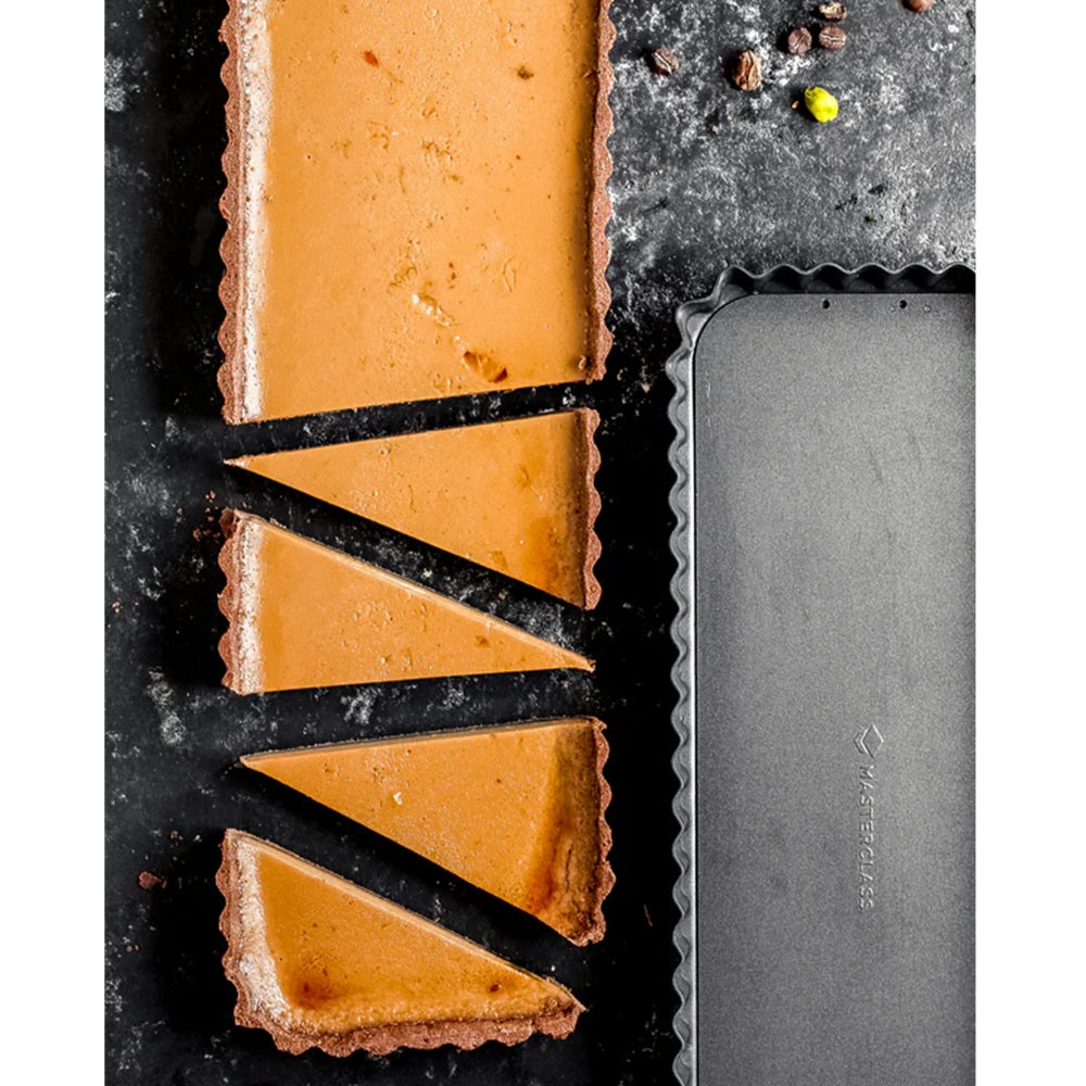 Butterscotch tart with a knife on a dark surface