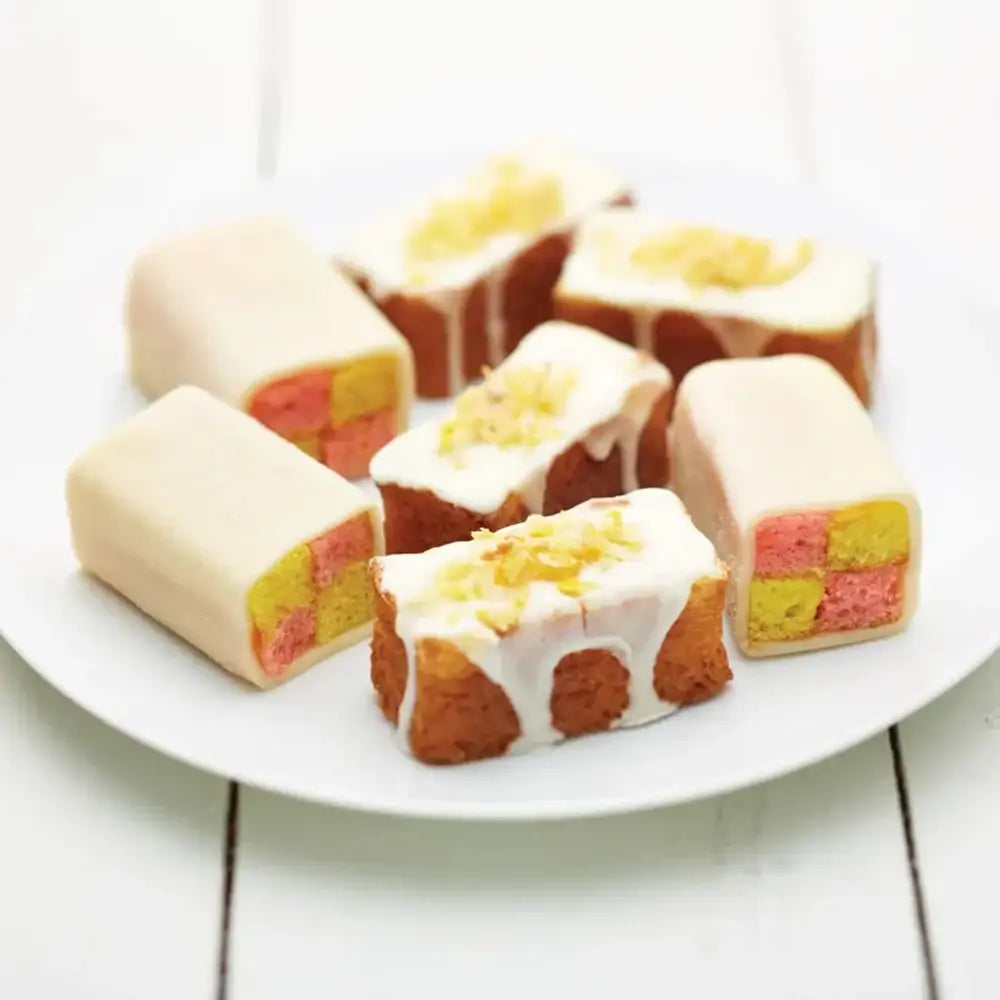 Colorful layered cake bars on a white plate with a white background