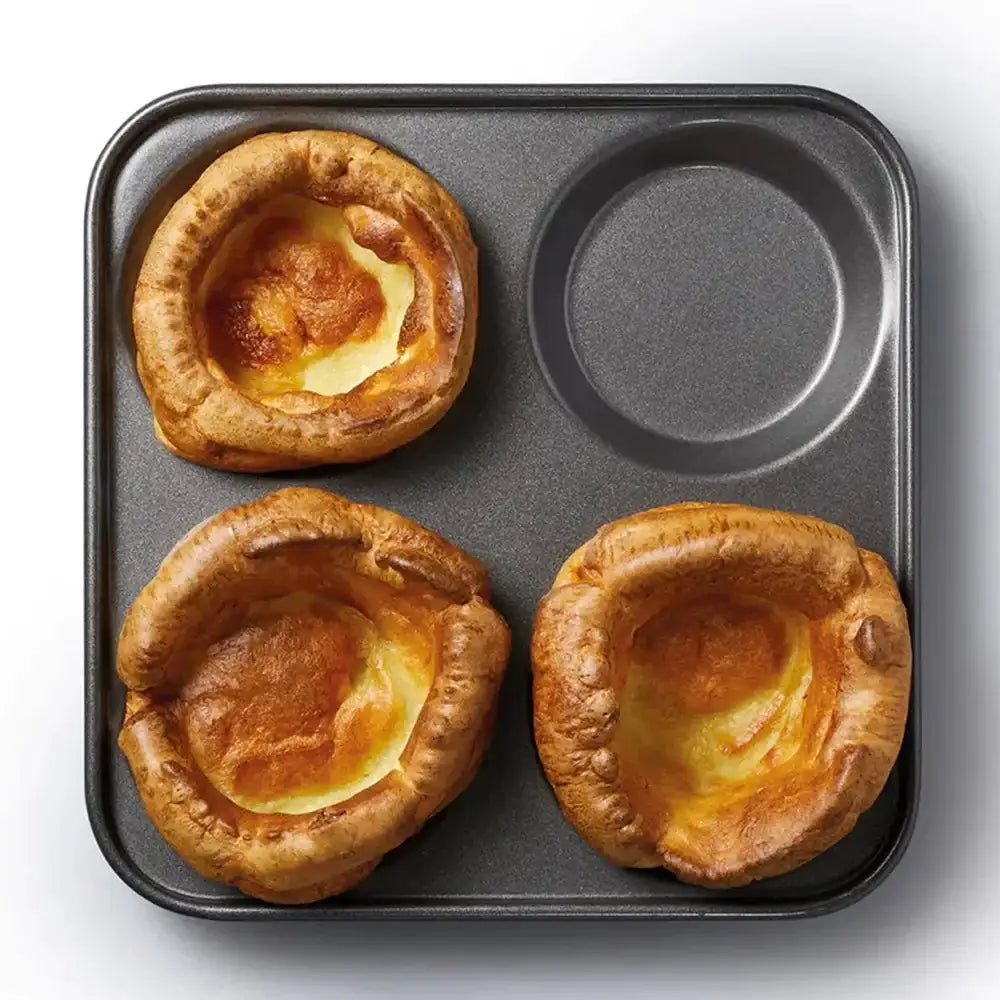 Three Yorkshire puddings in a muffin tin on a white background