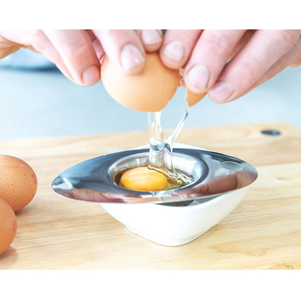 Person using an egg separator on a wooden surface