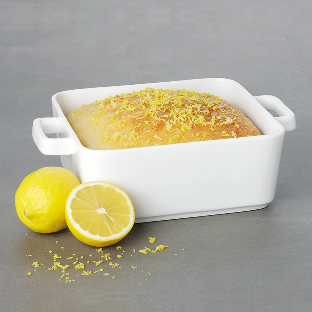 Baked dish in a white rectangular baking dish with lemons on a gray background