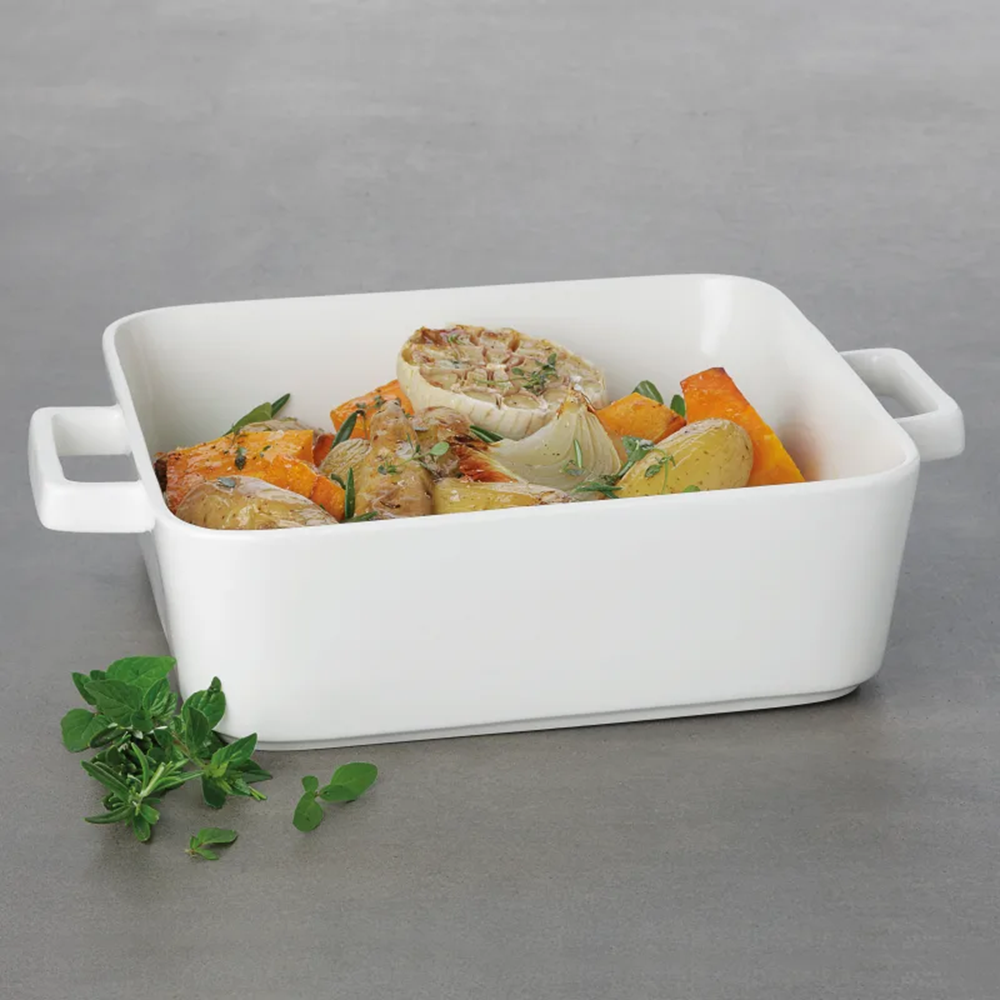 White rectangular baking dish with cooked vegetables on a gray background