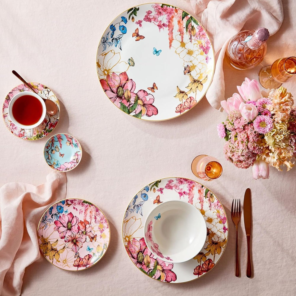 Floral dinnerware set on a table with tea and flowers.