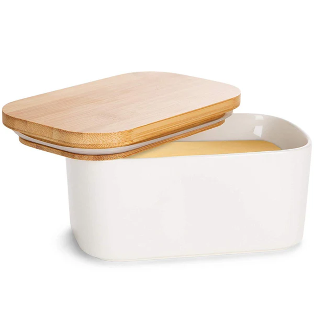 White ceramic butter dish with a wooden lid on a white background