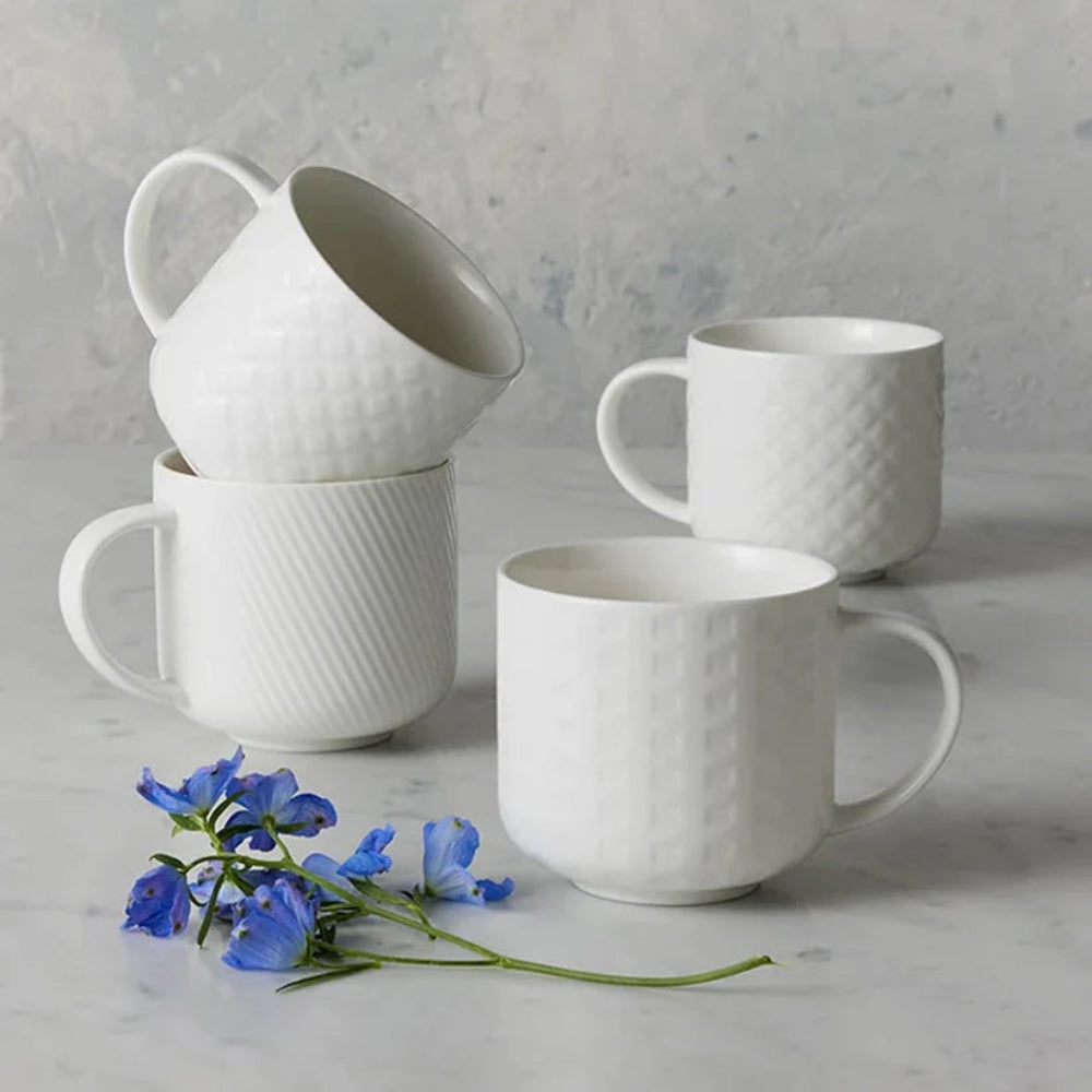 Four white mugs displayed on a light grey surface 