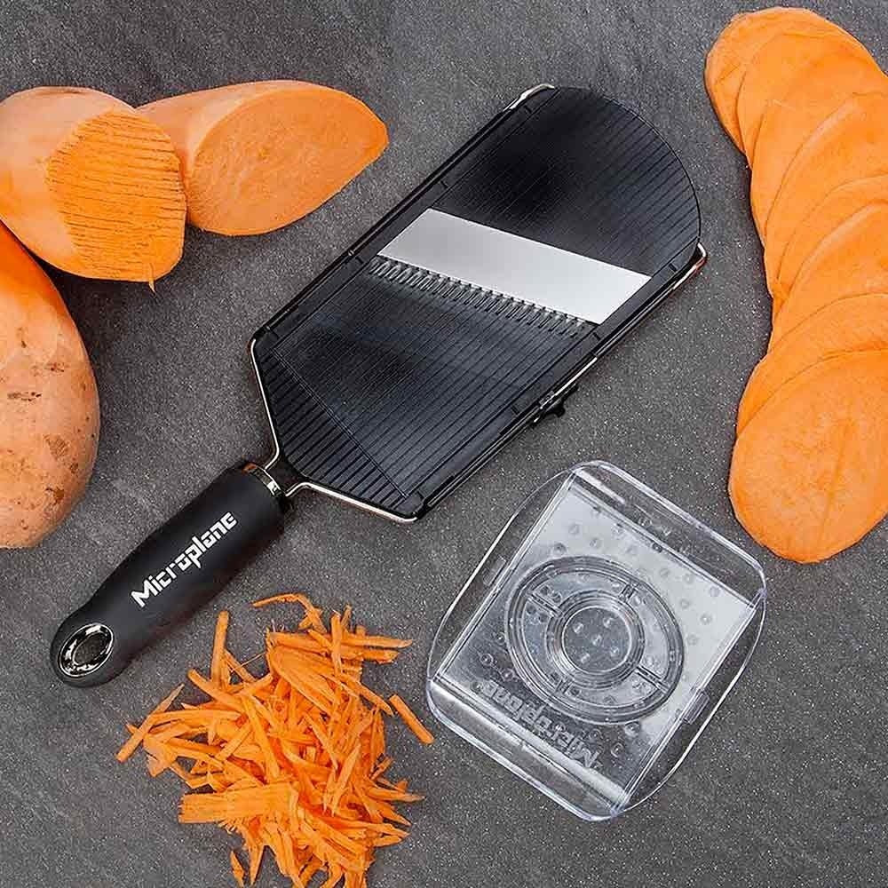 Microlane vegetable slicer with sliced carrots on a dark surface