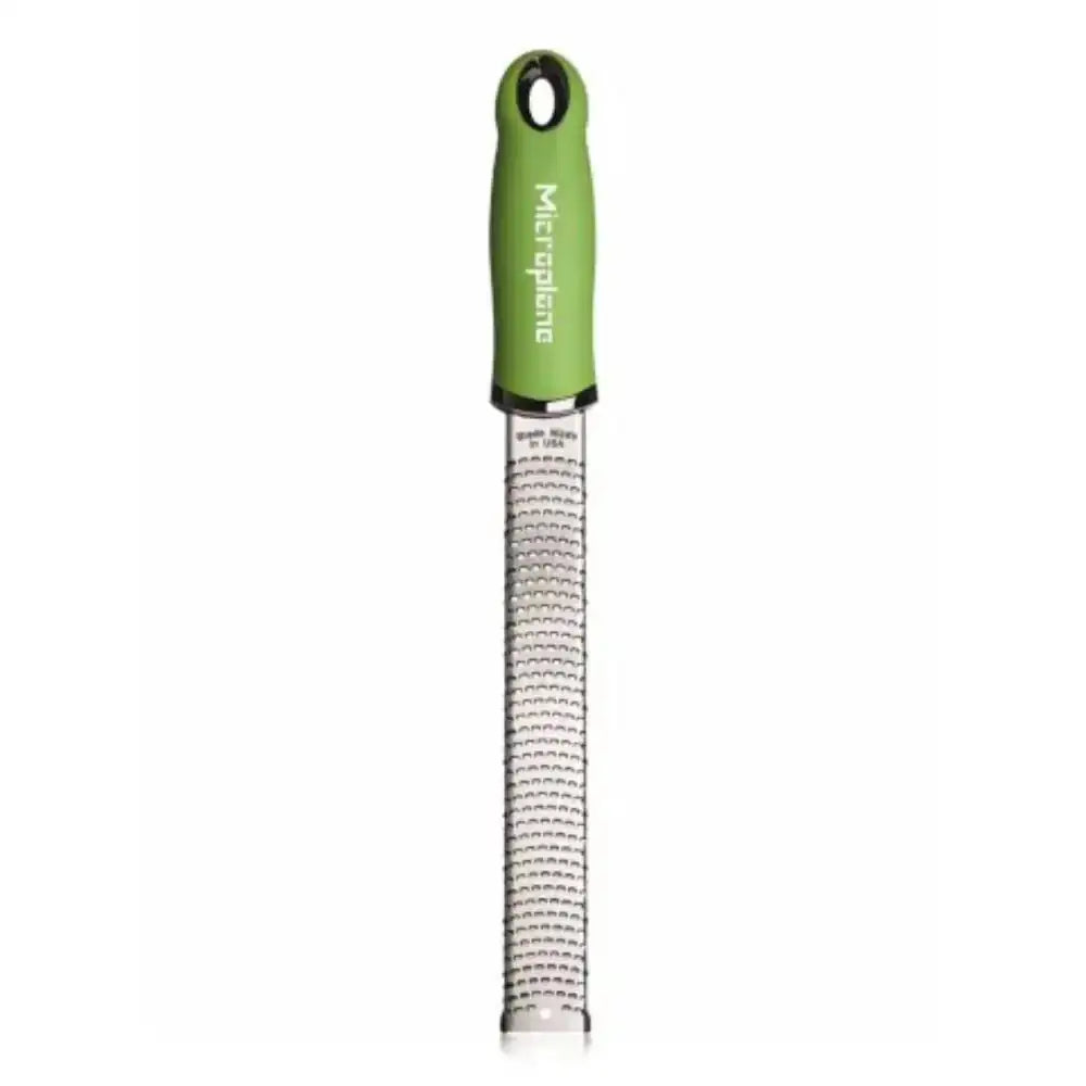 Green handheld grater with metal surface on a white background