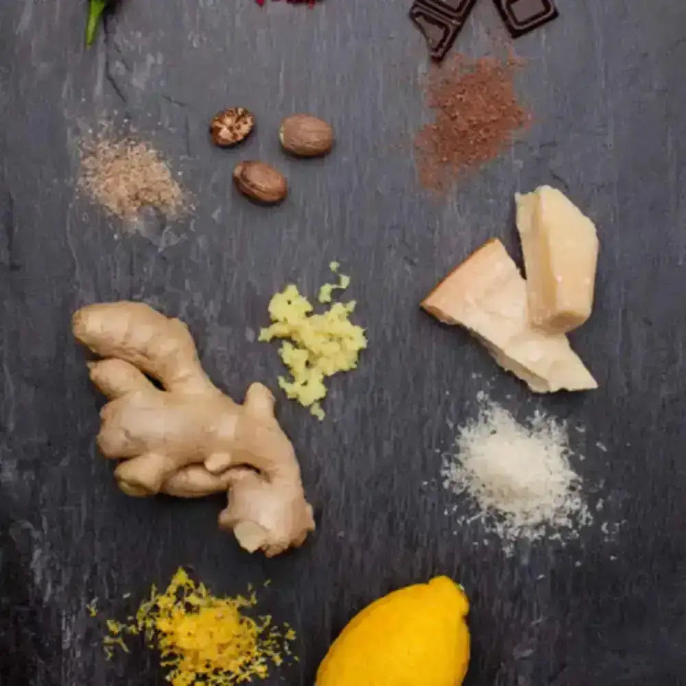 Spices and herbs including ginger, lemon, and various seeds on a dark surface
