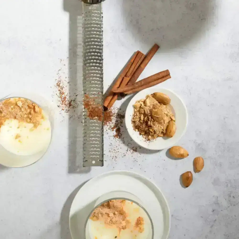 Dessert with cinnamon, nutmeg, and a grater on a light gray surface
