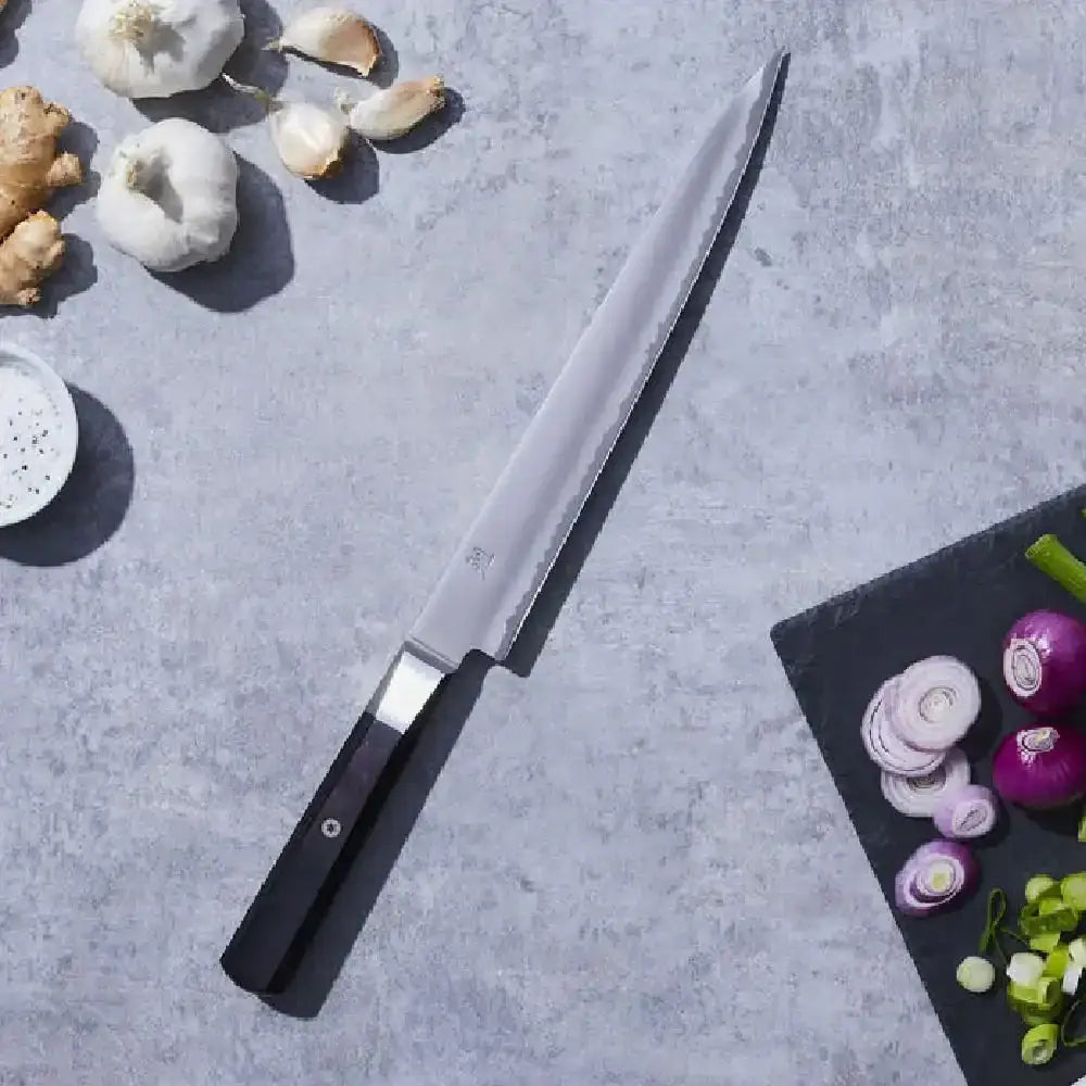 Knife on a gray surface with garlic and other ingredients around