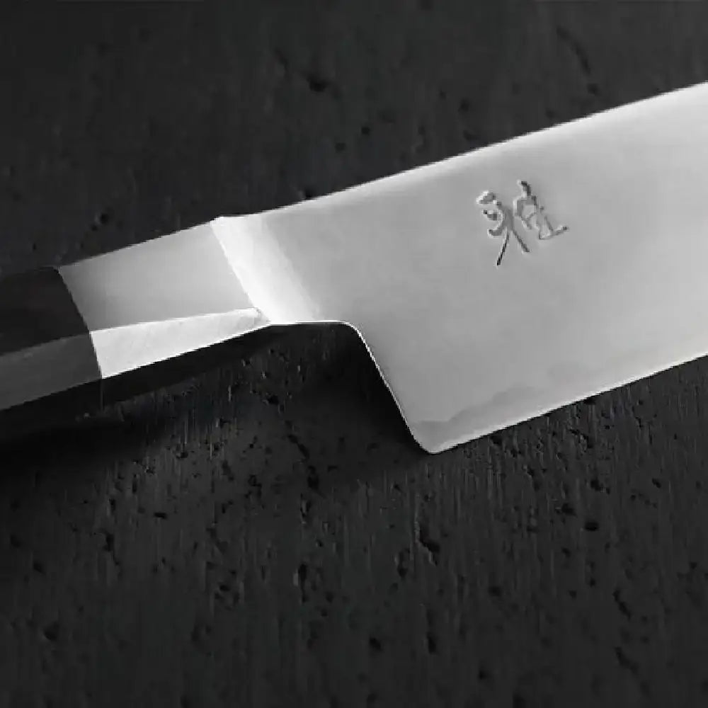Close-up of a chef's knife blade with a brand logo on a dark background