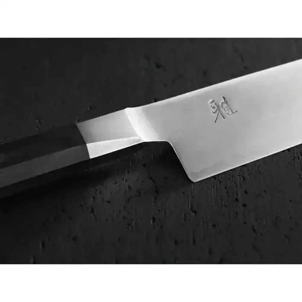 Close-up of a chef's knife with a brand logo on a dark surface