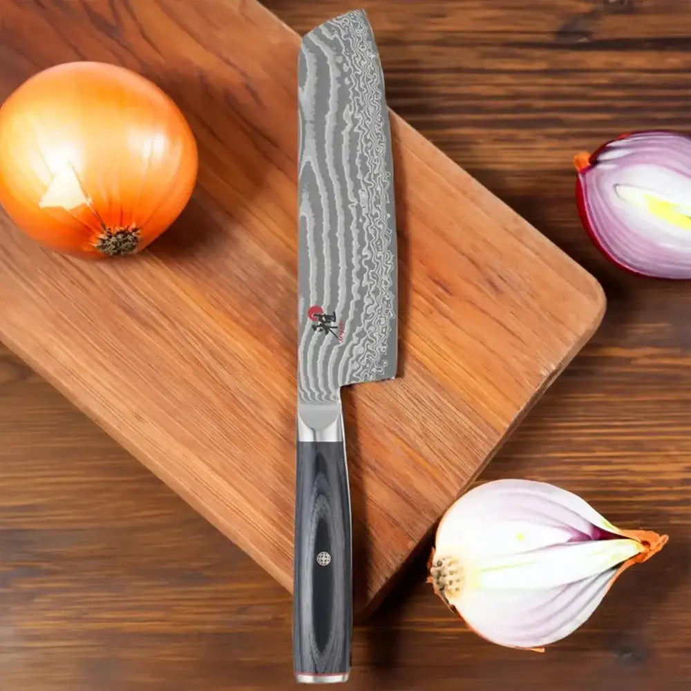 Chef's knife on a wooden cutting board with onions and garlic