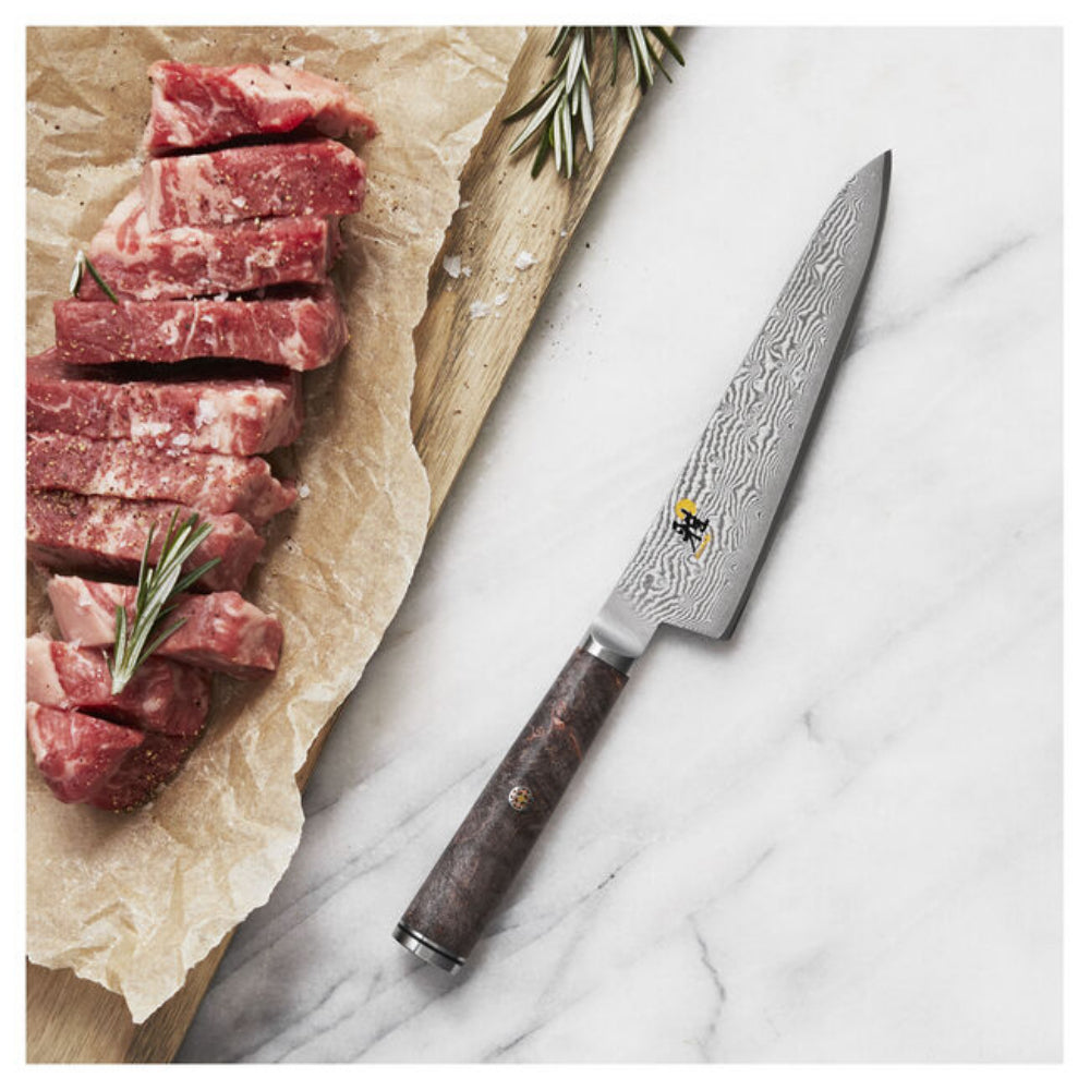 Sliced raw meat on a wooden board with a Damascus knife on a marble surface