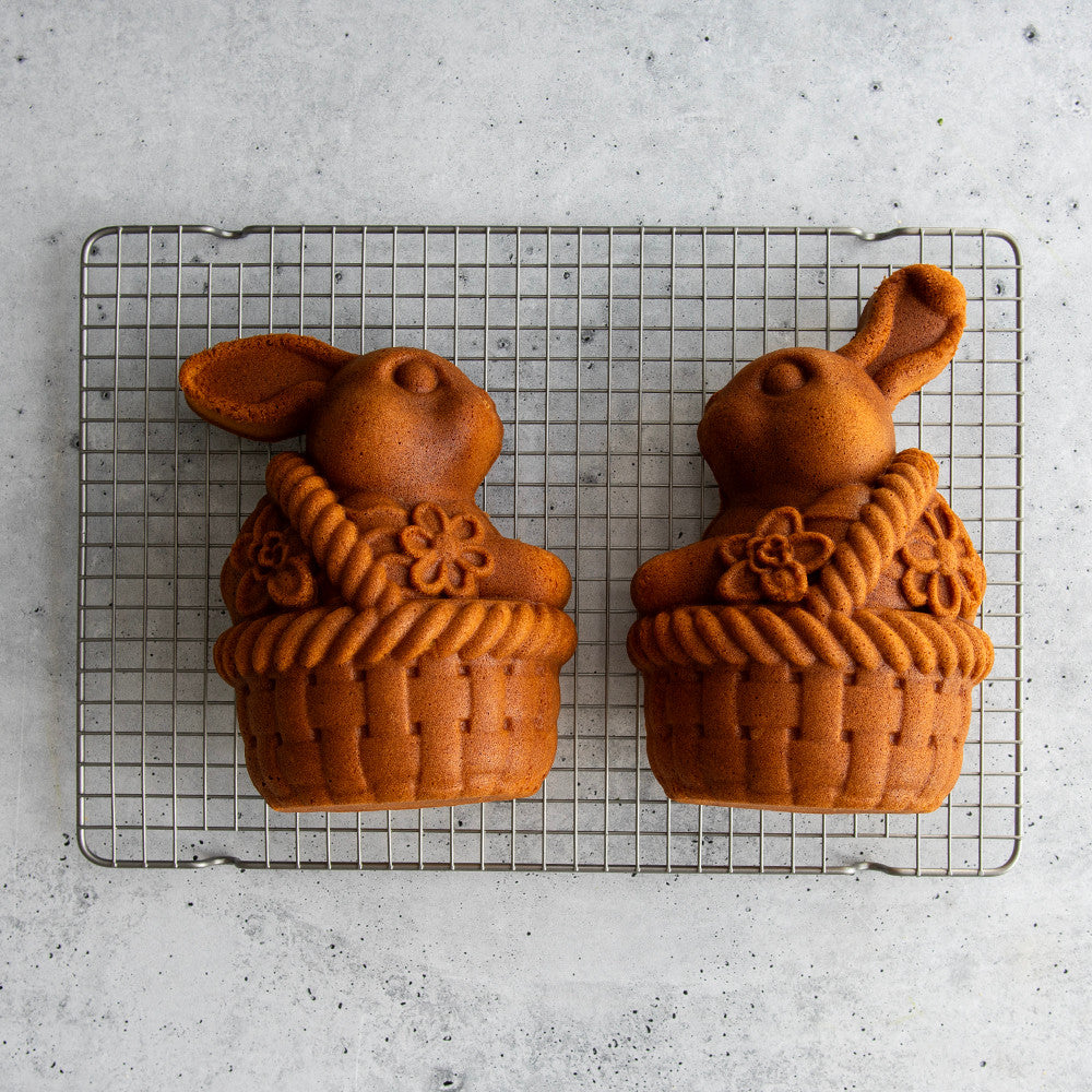 Two bunny-shaped cakes on a cooling rack with a light gray background