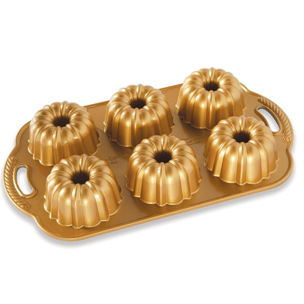 Gold Bundt cake pan with six individual mold sections on a white background