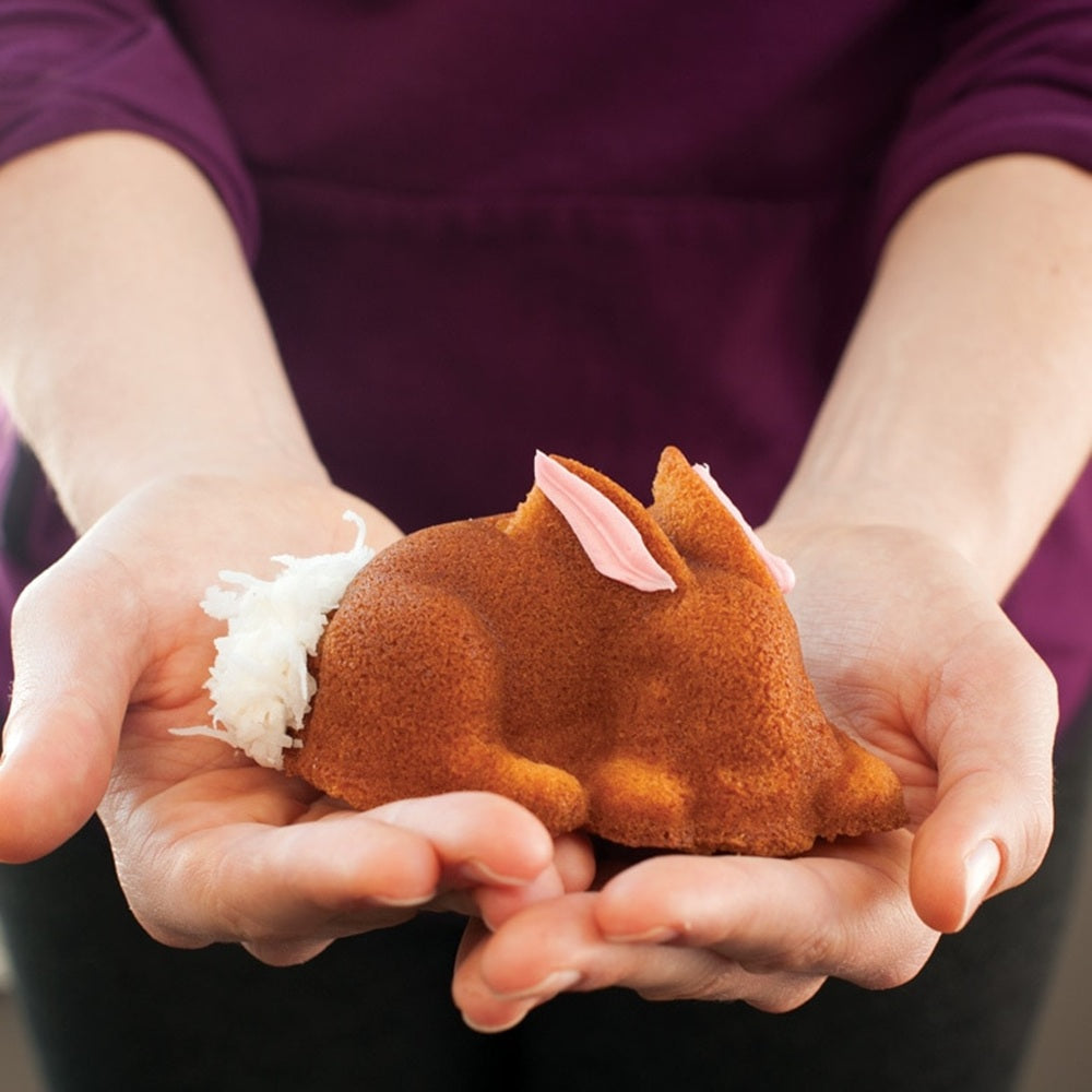 Small brown plush toy held in hands against a blurred background