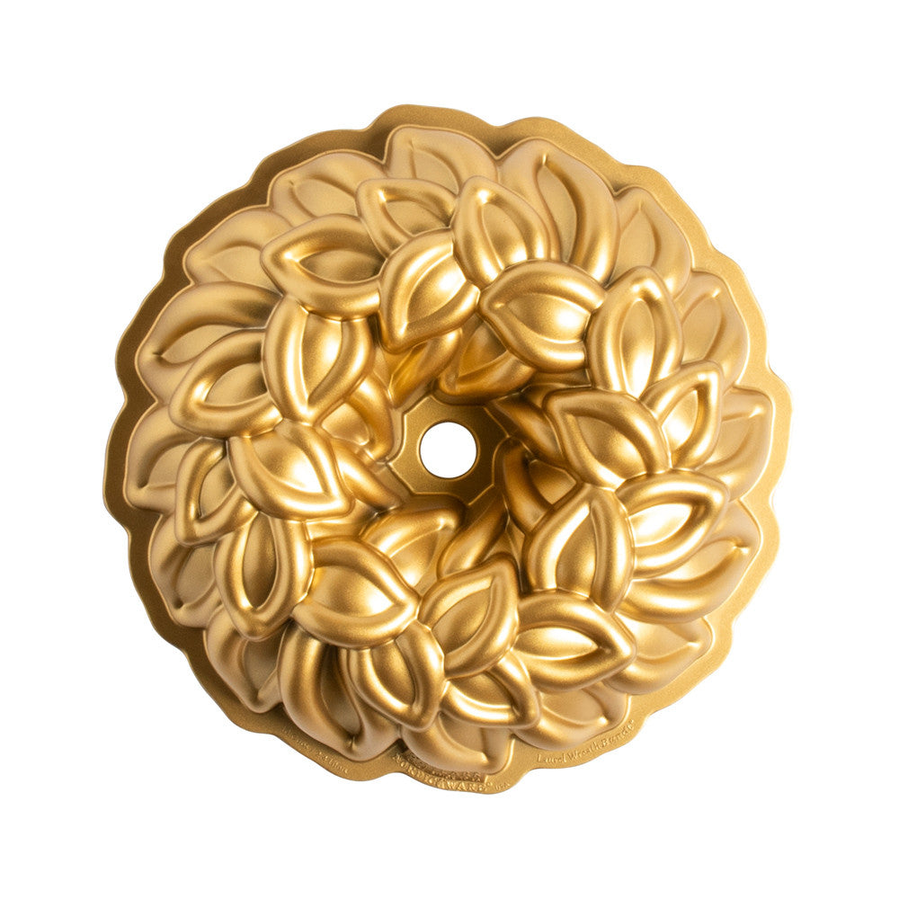 Gold decorative cake mold with intricate leaf pattern on a white background