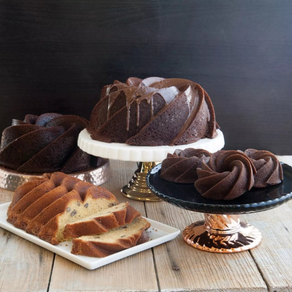 Three chocolate bundt cakes on stands with a dark background