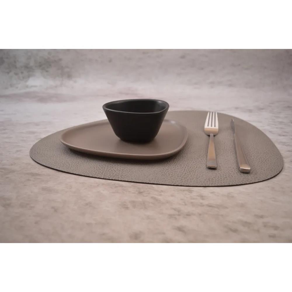 Dinner set with a bowl, plate, fork, and knife on a textured placemat.