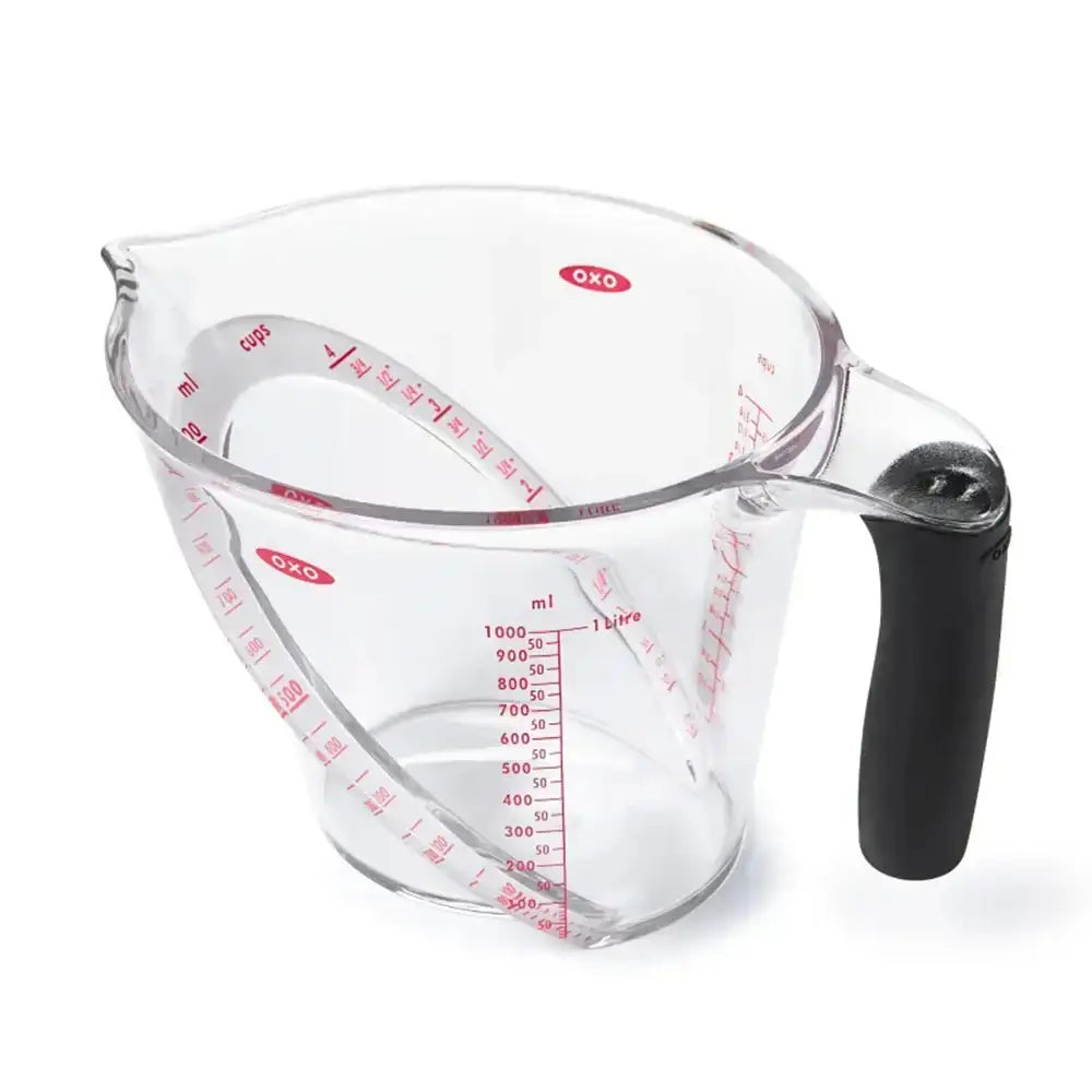 Clear measuring cup with black handle and red measurement markings on a white background