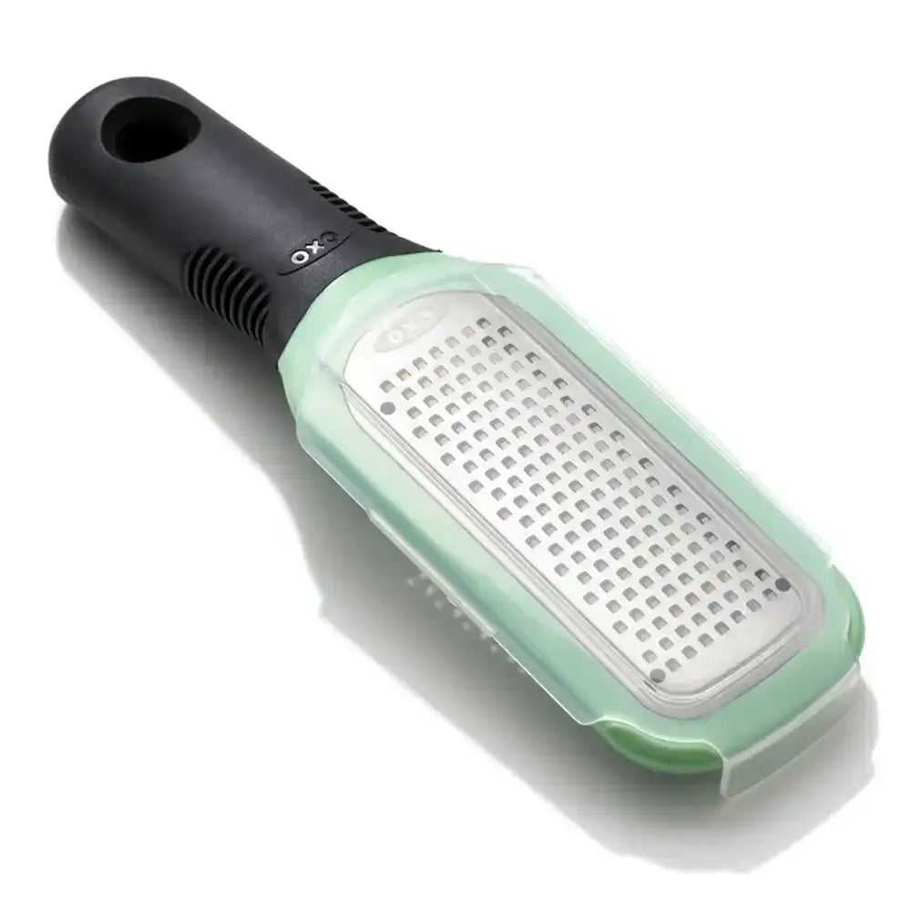 Handheld grater with black handle and green body on a white background
