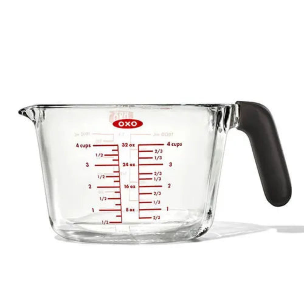 Clear measuring cup with black handle and red measurement markings on a white background