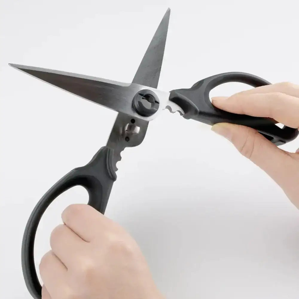 Person holding a pair of black-handled scissors against a white background