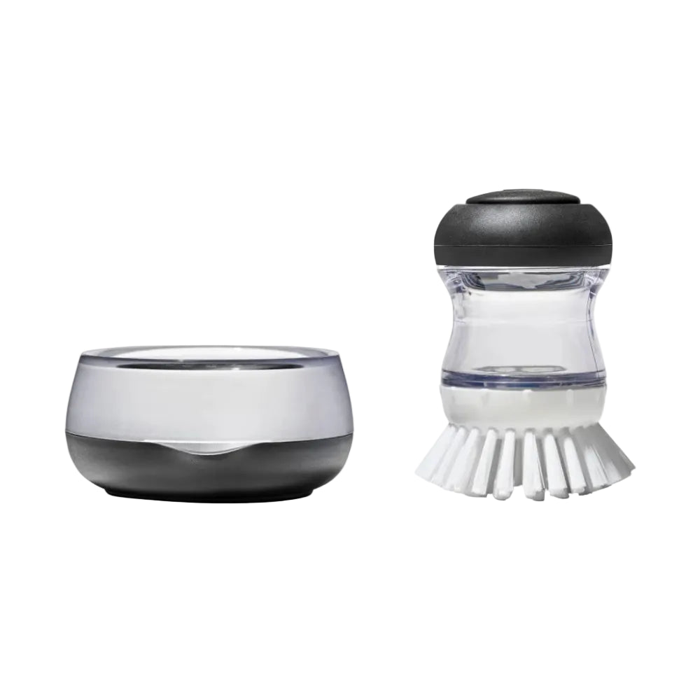 Clear kitchen scrubber with black bristle head and black base on a white background