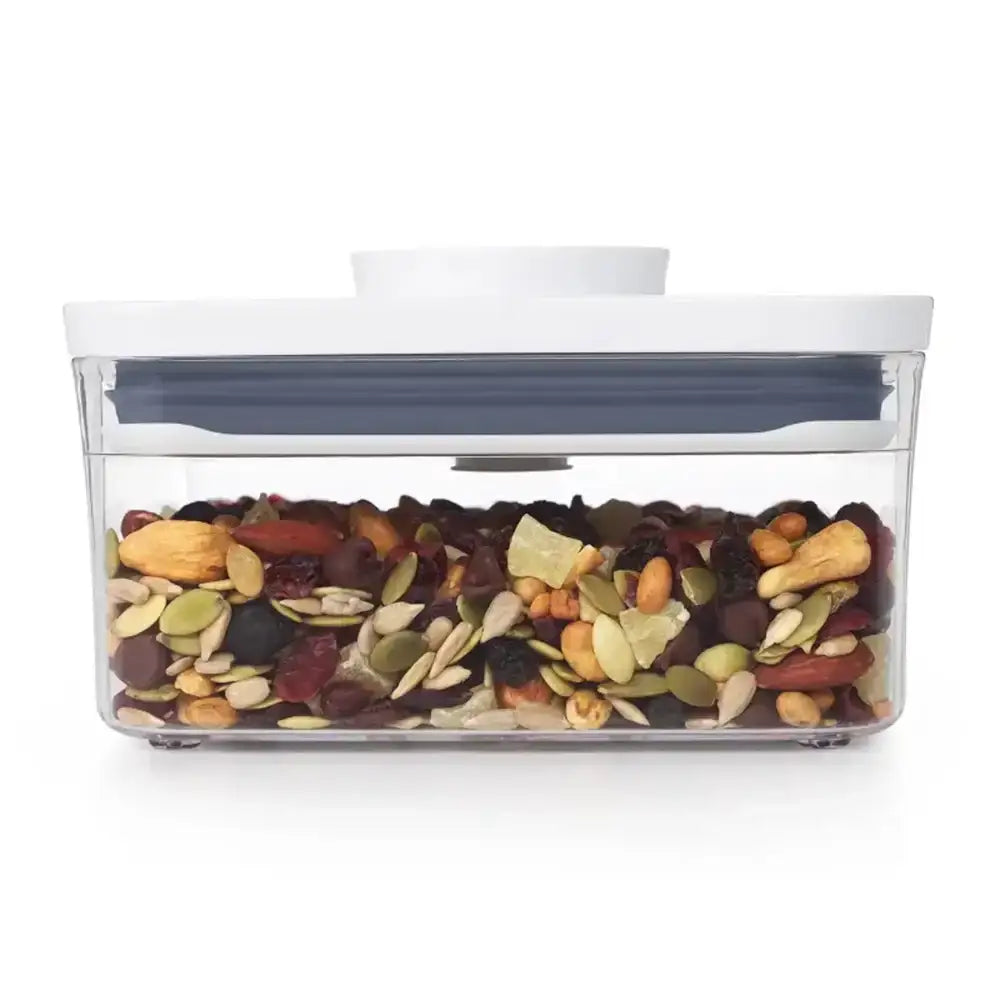 Clear container with a white lid filled with a mix of nuts and seeds on a white background