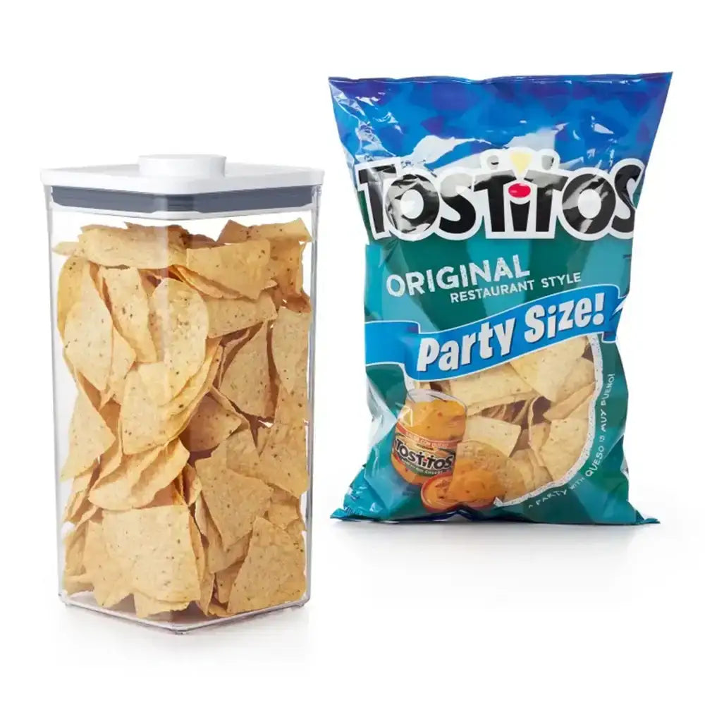 Tostitos Original Restaurant Style tortilla chips in a clear container next to a blue party size bag on a white background
