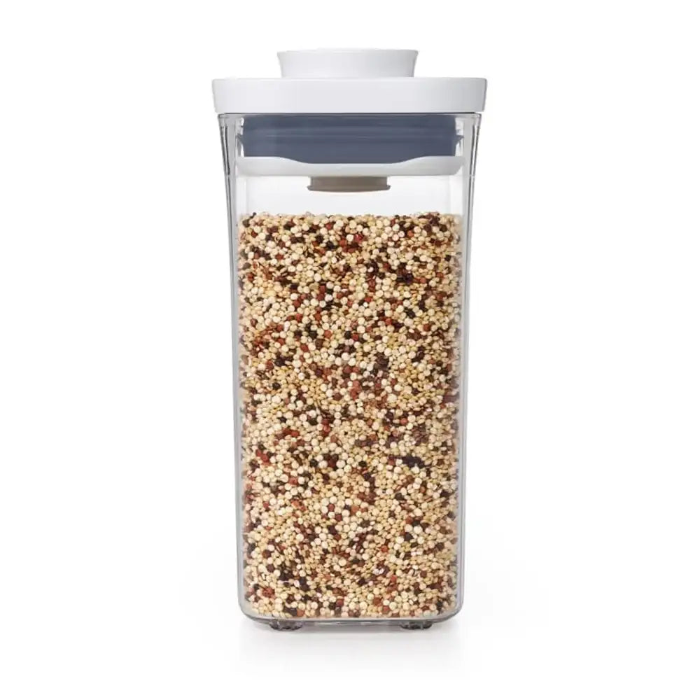 Clear container with lid filled with multicolored quinoa on a white background