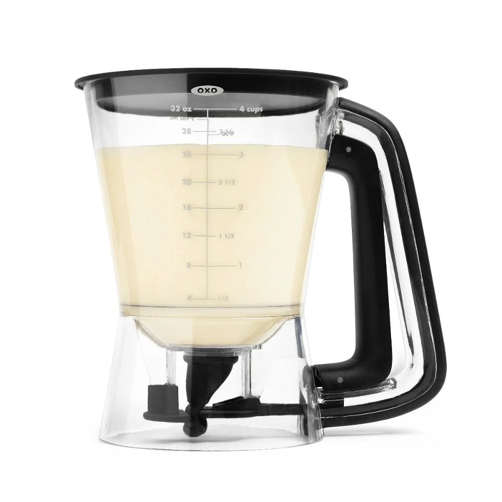 Clear batter dispenser with black handle filled with liquid on a white background