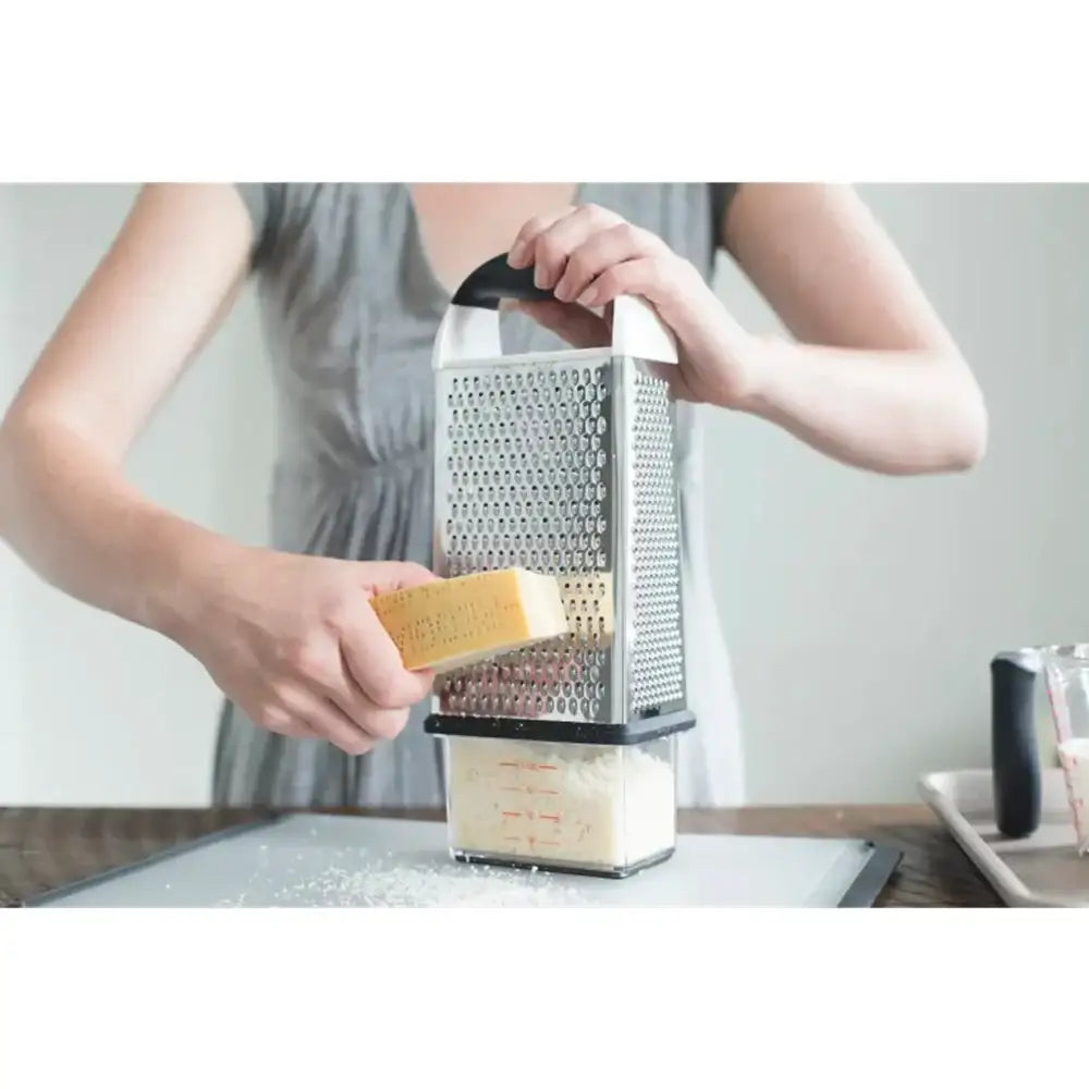 Person using a box grater with a clear container to collect grated ingredients.