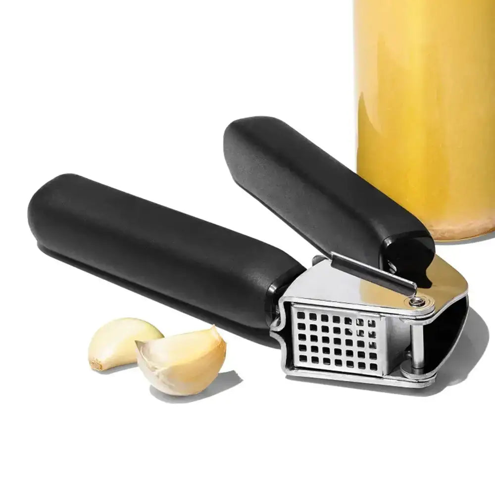 Garlic press with garlic cloves on a white background