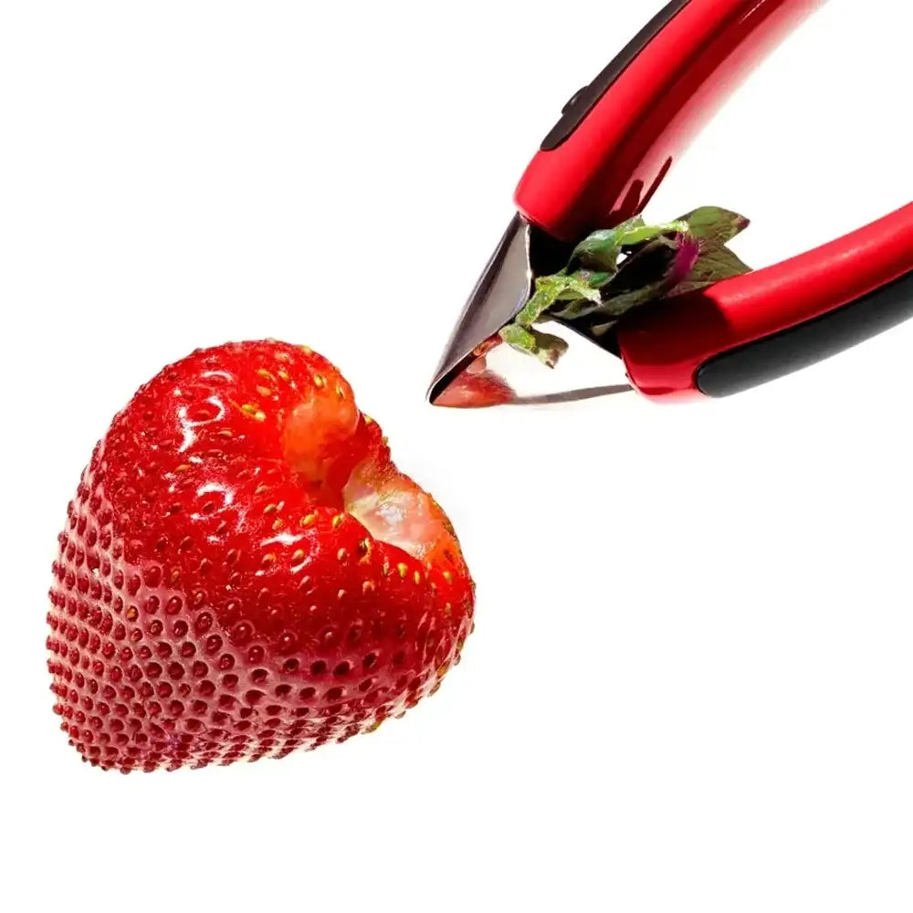 Strawberry being cut with a red and black strawberry huller on a white background