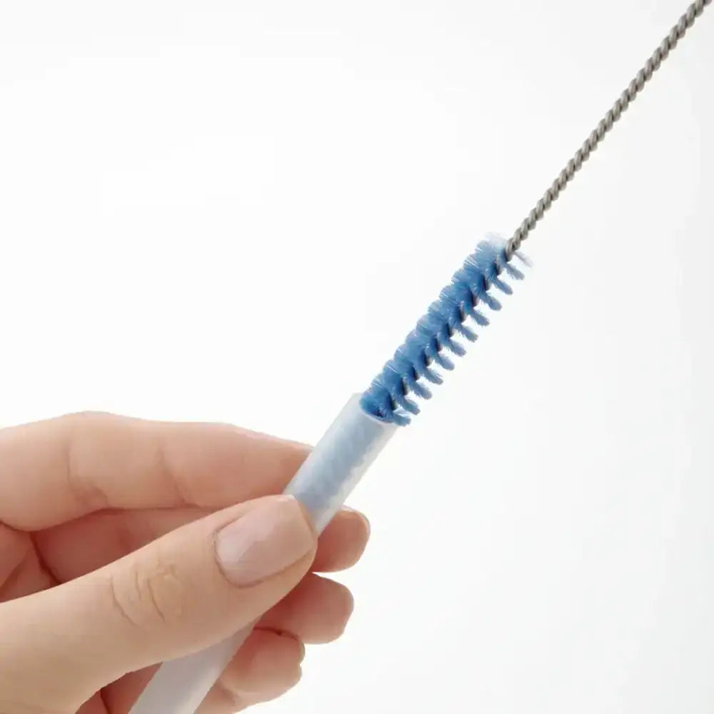 Hand holding a white and blue straw cleaning brush on a white background