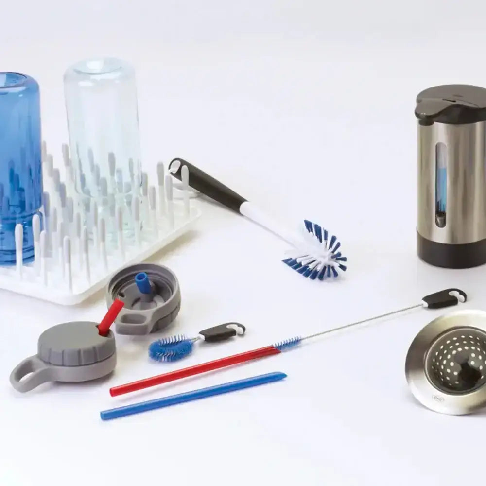 Collection of kitchen cleaning tools including straws, brushes, and a water bottle on a white background