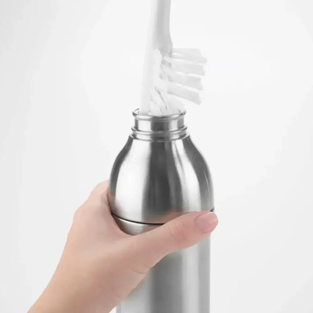 Hand holding a stainless steel bottle with a white brush inside against a light gray background