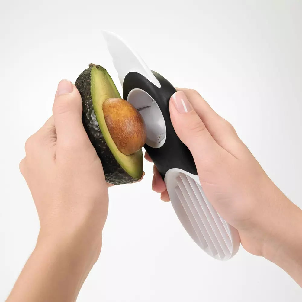 Hands using the oxo avocado slicer to remove the pip 