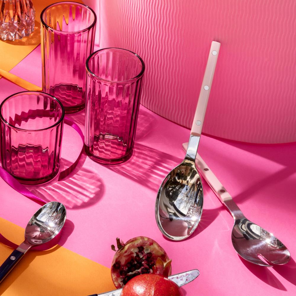 Pink glass tumblers and silver spoons on a pink and orange surface