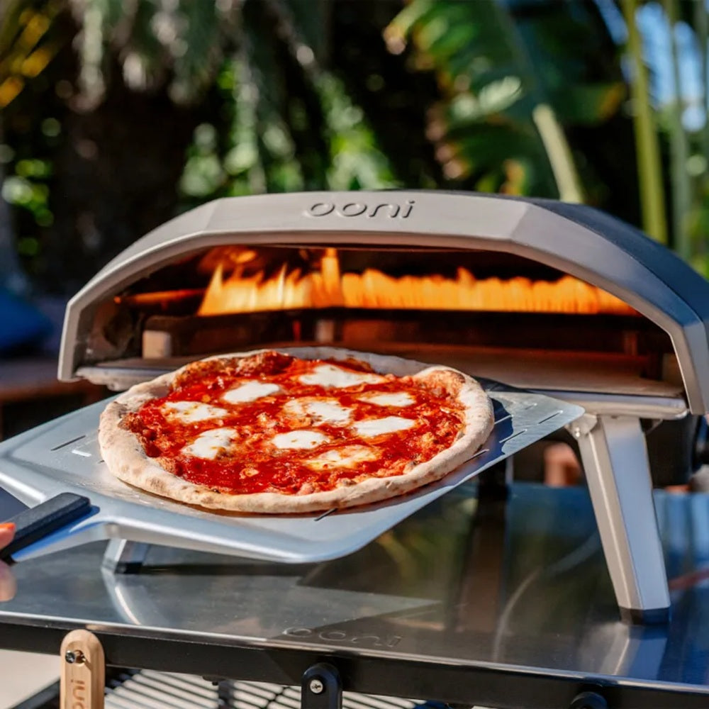 Ooni pizza oven with a pizza inside, outdoors.