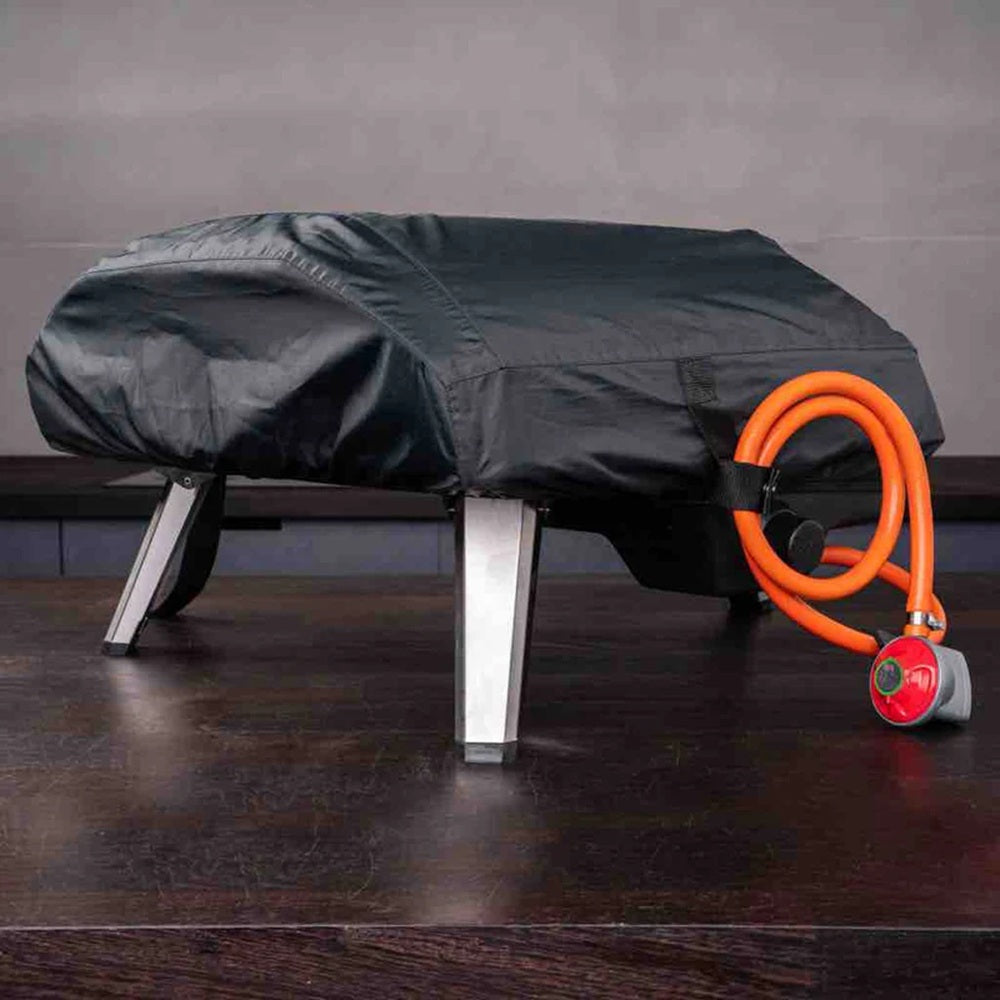Black outdoor furniture cover with an orange hose and red valve on a wooden floor.