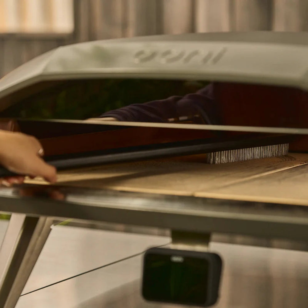 Person cleaning an Ooni pizza oven 